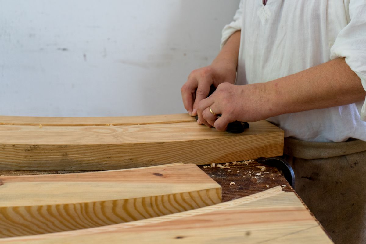 Handwerkliches Hobeln eines Massivholzbretts in der Werkstatt